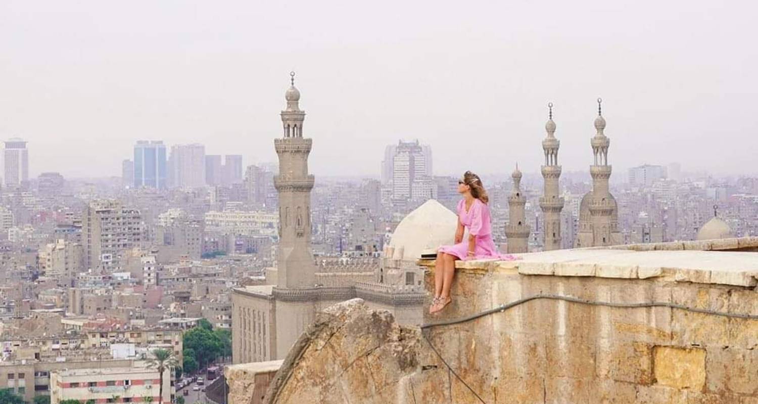 Cairo Woman sitting in the sun against a backdrop of Cairo buildings
